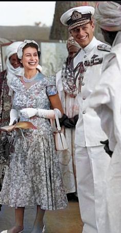 a man and woman dressed in white are standing next to each other with hats on