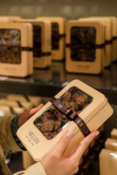 a person holding up a box with chocolates in it's hands and other boxes behind them