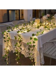 the table is covered with greenery and lit candles