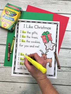 a hand holding a marker over a christmas poem with crayons and pencils