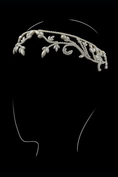 a woman's head wearing a tiara with pearls and leaves on the side