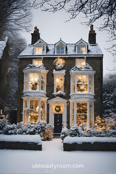 a large house covered in snow with christmas lights on the windows and wreaths all around