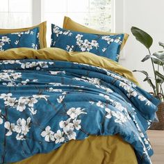 a blue and yellow comforter with white flowers on it in front of a window