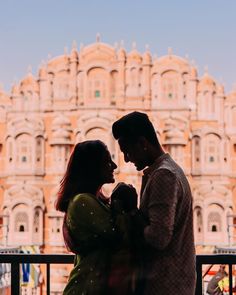 a man and woman standing next to each other in front of a building