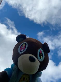 a teddy bear with big eyes standing in front of the sky