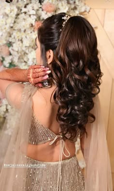 a woman with long hair wearing a wedding dress and holding her hands to her face