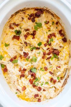 a casserole dish in a white bowl with bacon and green garnish