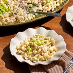 two plates filled with macaroni salad on top of a wooden table