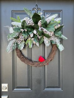 a wreath is hanging on the front door with a red bird sitting on it's side