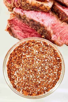 steak seasoning in a glass bowl next to sliced meat