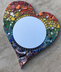 a heart shaped mirror sitting on top of a cement floor next to a white wall