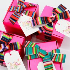 several colorful striped bows are in pink boxes