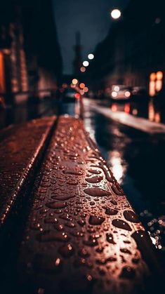 raindrops on the side of a wet street at night with buildings in the background