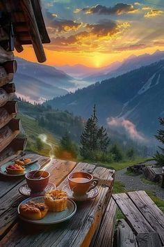 a wooden table topped with plates of food on top of a mountain covered in clouds