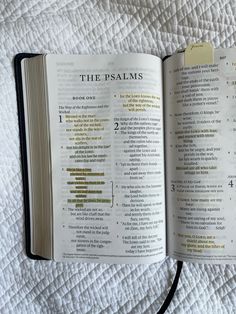 an open bible on a bed with the words, the psalms written in gold and black