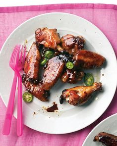 a white plate topped with chicken wings covered in bbq sauce and jalapenos