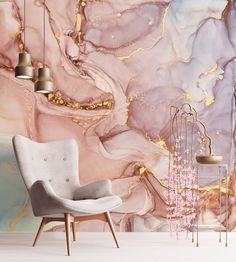 a chair in front of a wall with pink and gold paint on it, next to two lamps