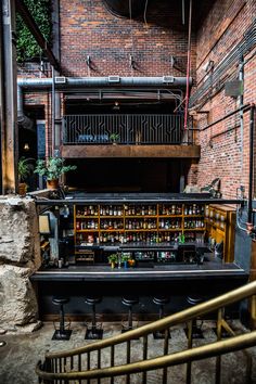 a bar with lots of bottles on it in the middle of a room filled with stairs