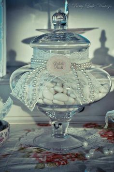 a glass jar filled with white pearls on top of a table