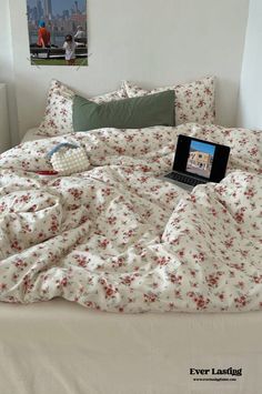 an open laptop computer sitting on top of a bed covered in white and red sheets