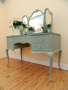 a blue dresser with flowers and a mirror on it