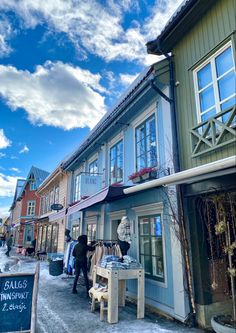 several people are walking down the street in front of some buildings with snow on them