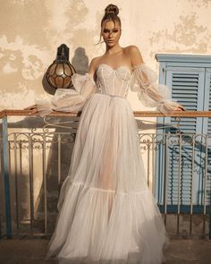 a woman in a white dress standing on a balcony