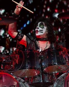 a man with makeup on his face and holding drums in front of him, while he is