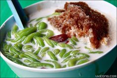 a bowl filled with green beans and some kind of meat on top of it next to chopsticks