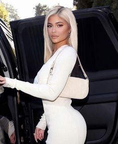 a woman in a white dress getting out of a car