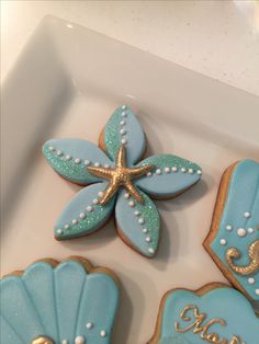 decorated cookies in the shape of seashells and starfish on a white tray