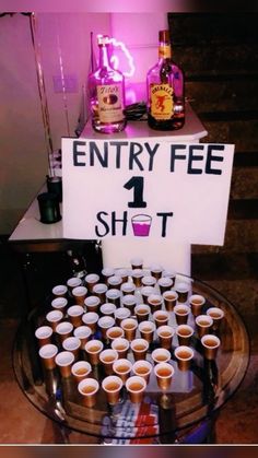 there is a sign that says entry fee 1 shot on the table with cups in front of it