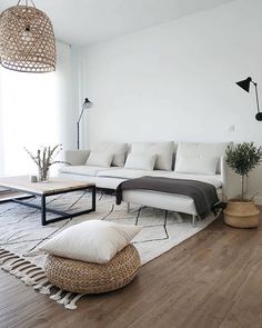 a living room with white couches and pillows on top of the floor, next to a large window