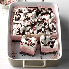 a pan filled with desserts covered in white frosting and peppermint bits