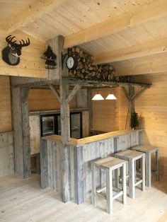 a kitchen area with stools, counter and clock on the wall in a log cabin