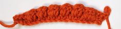 an orange piece of yarn that has been crocheted to look like a crown