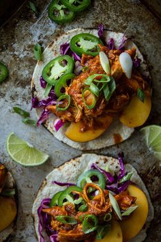 three tortillas topped with meat and vegetables on top of a baking sheet next to lime wedges