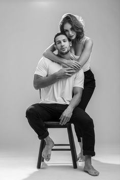 a man sitting on top of a chair holding a woman