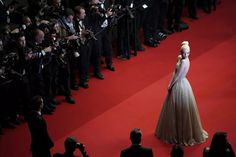 lady in white dress walking on red carpet with cameras surrounding her and people taking pictures