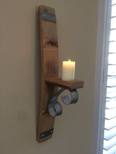 a candle that is sitting on a wooden shelf next to a window with shutters