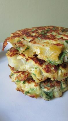 a stack of food sitting on top of a white plate covered in cheese and veggies