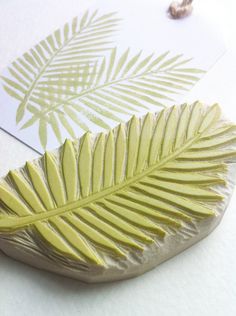 a close up of a leaf on a piece of paper next to some beads and a bead