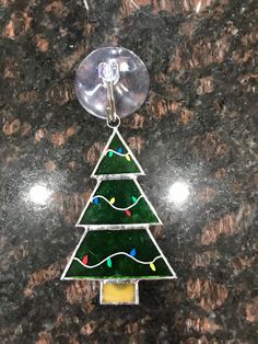 a glass christmas tree ornament hanging on a marble counter