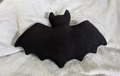 a black bat laying on top of a white blanket