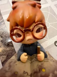 a small figurine is sitting on top of a piece of paper and wearing glasses