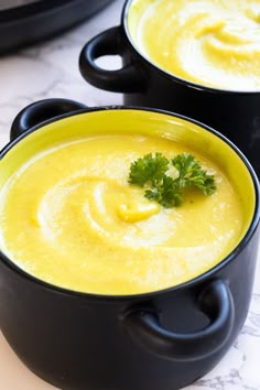 two black bowls filled with soup and garnished with parsley on the side