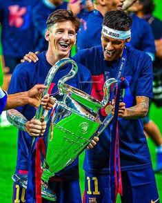 two soccer players are holding up the trophy