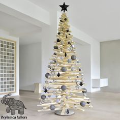 a wooden christmas tree with black and white ornaments on it's branches in an empty room