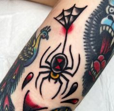 a close up of a person's arm with a spider and bird tattoos on it