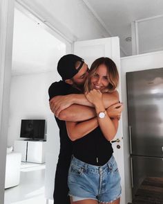 a man and woman hugging in front of a refrigerator freezer with their arms around each other